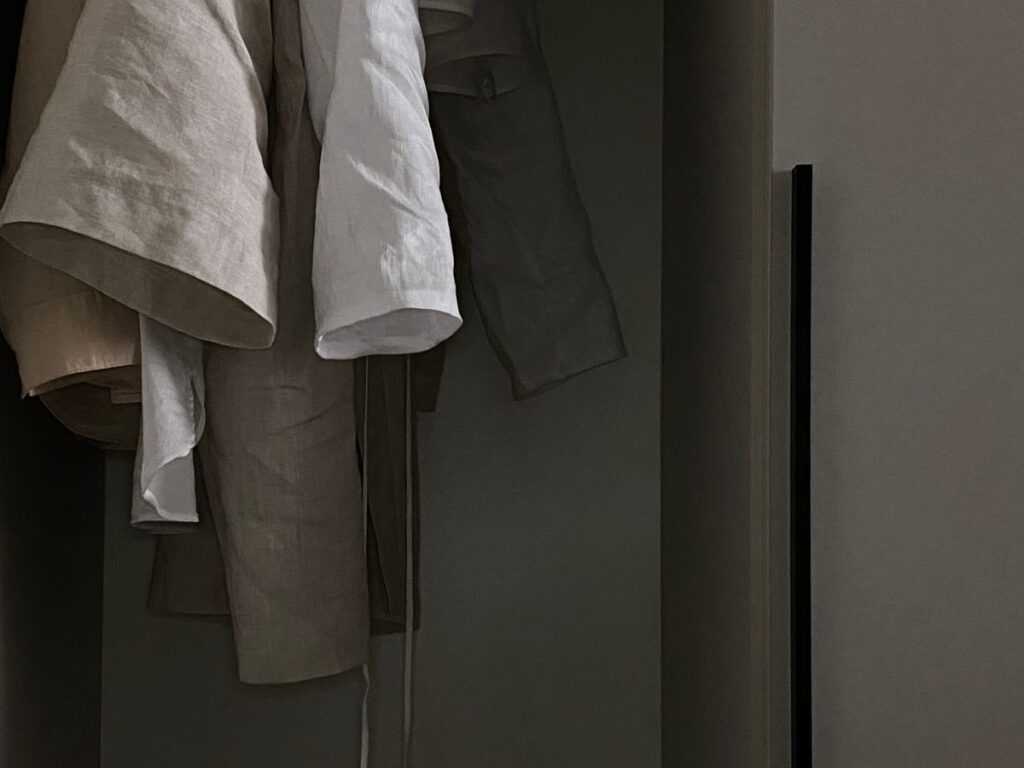 Softly lit decluttered closet with clothes on wooden hangers