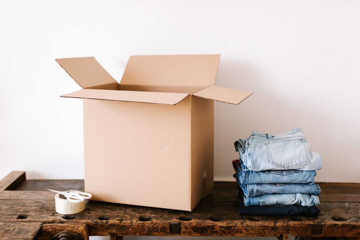 Folded clothes beside a box ready to store off-season clothes