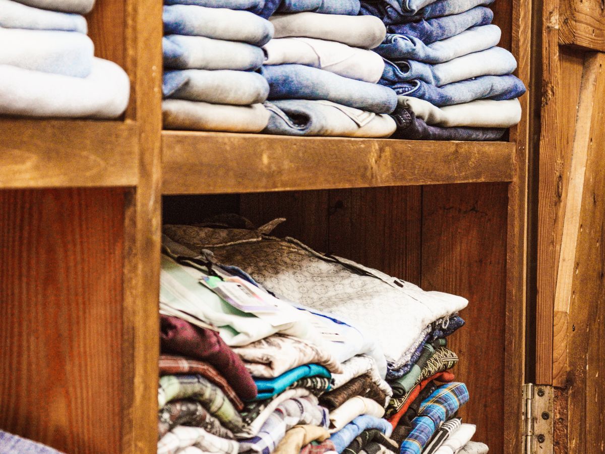 Organize a tiny closet with neatly folded clothes on wooden shelves