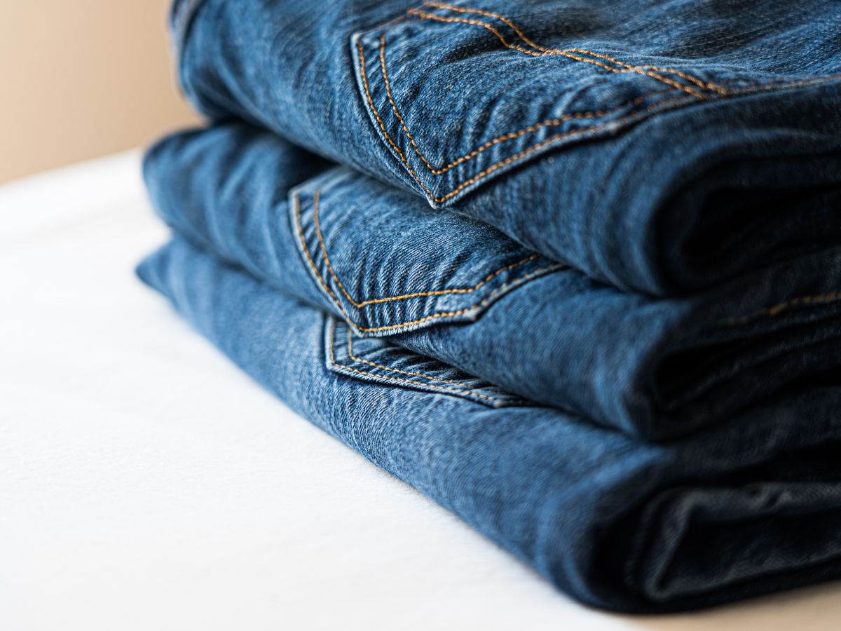 A stack of folded dark denim jeans washed to keep their color