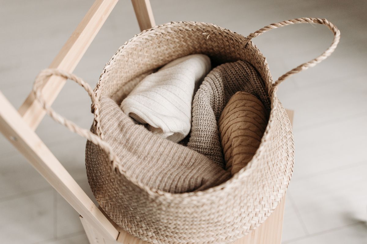 Folded knitted garments stored in a woven basket