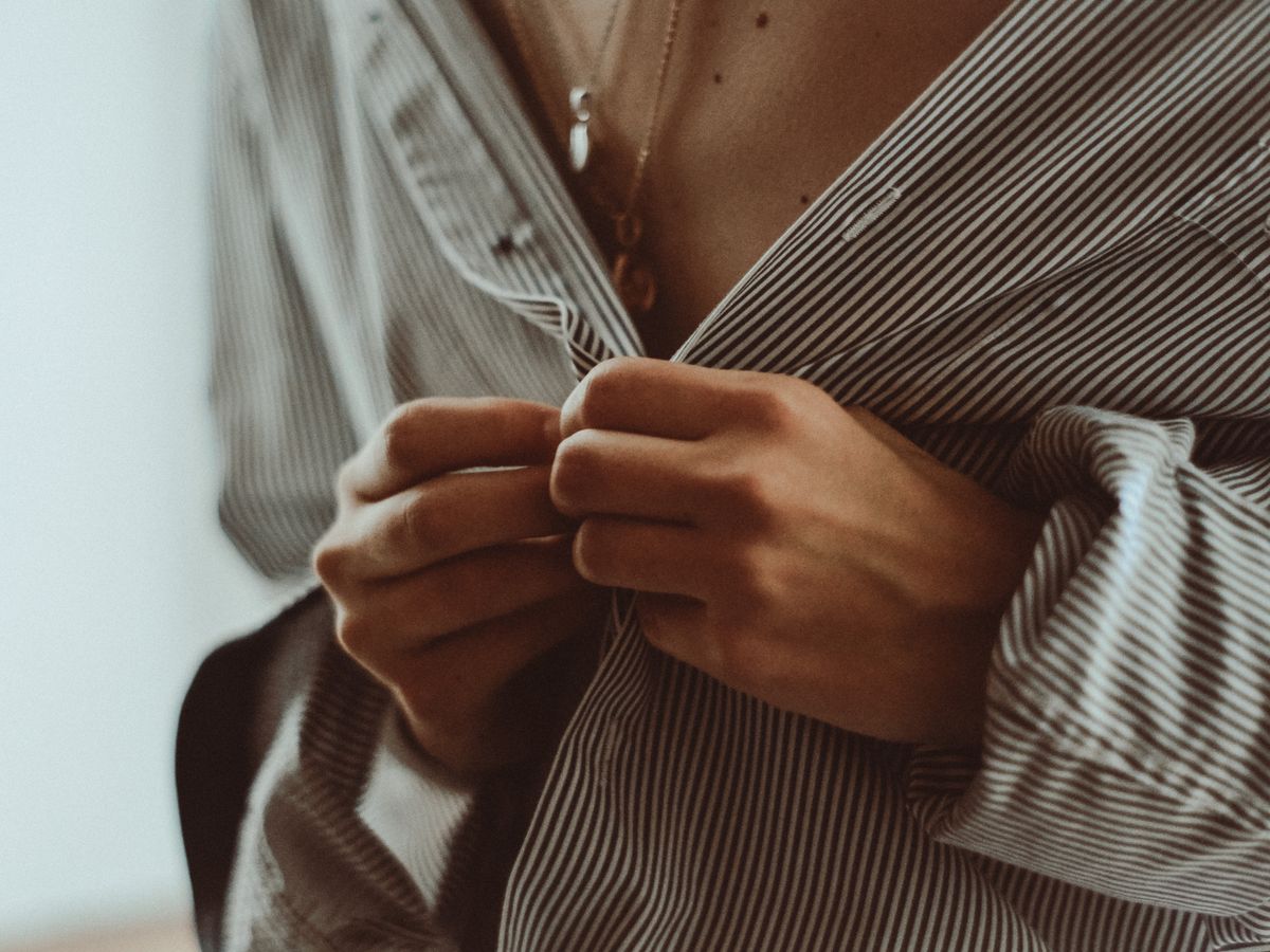 Hands buttoning a shirt while getting dressed in a hurry