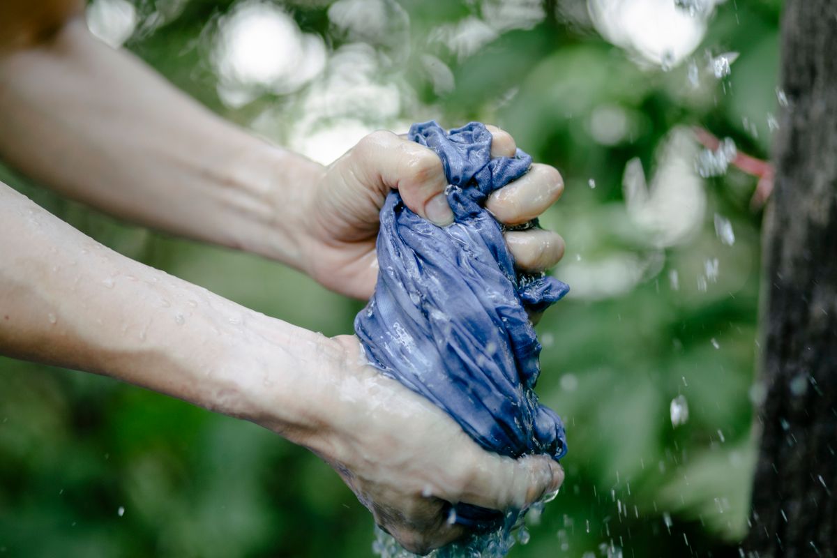 Hands gently hand washing delicate fabric in cool water without wringing