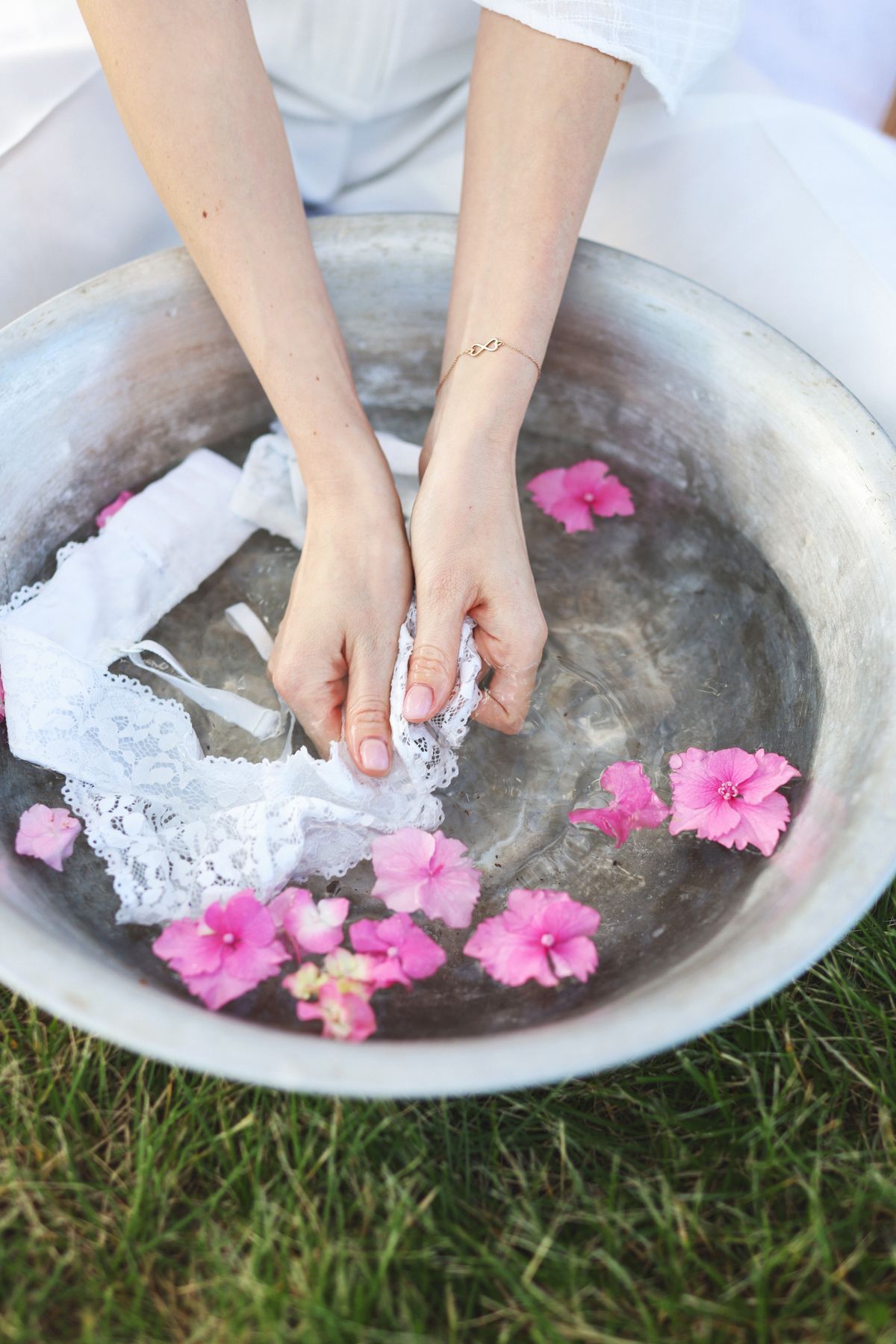 Hands gently washing delicate stained fabric in a bowl of cool water