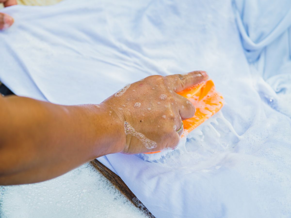 Handwashing a white shirt in a basin to treat a protein stain