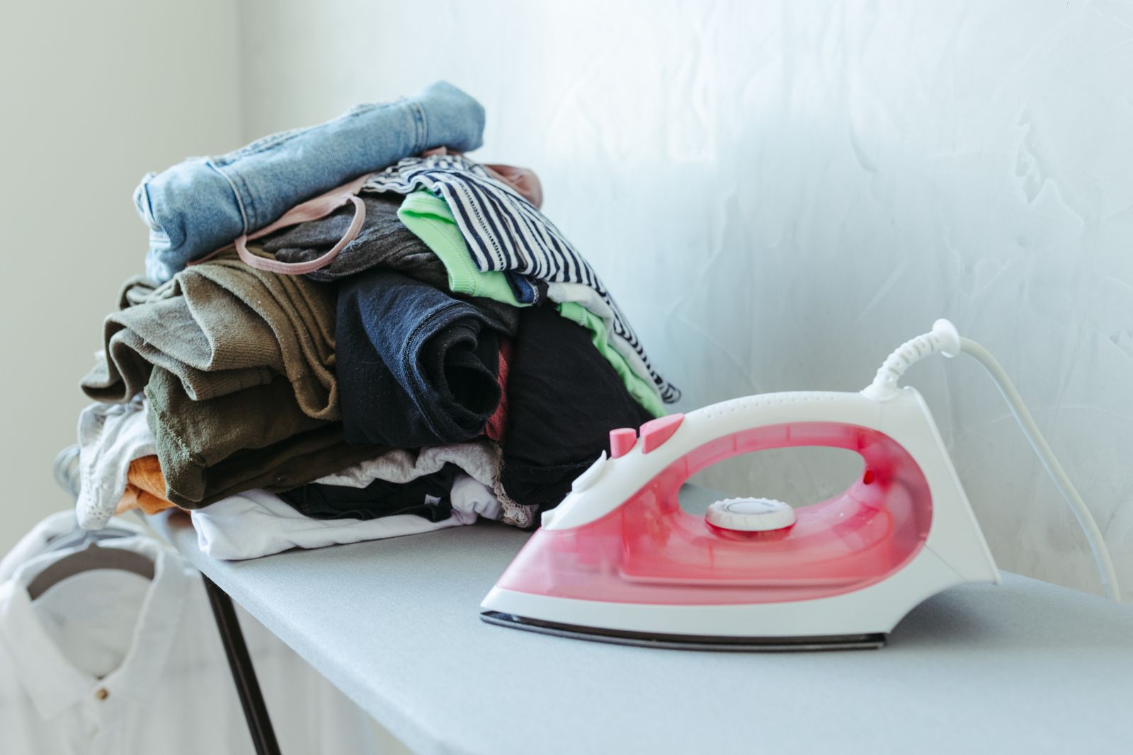 Freshly ironed clothes stacked beside an iron in a small space