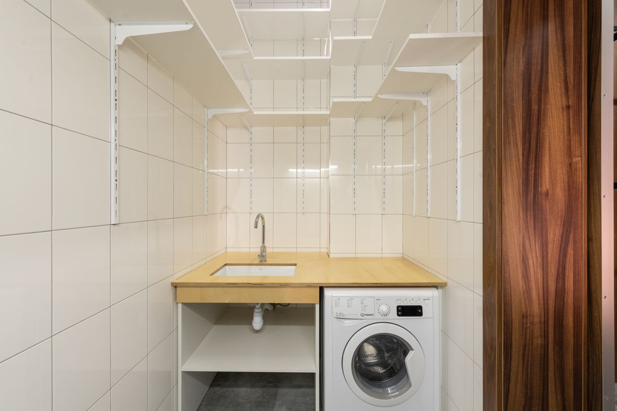 Minimalist laundry closet using vertical shelving above the washing machine