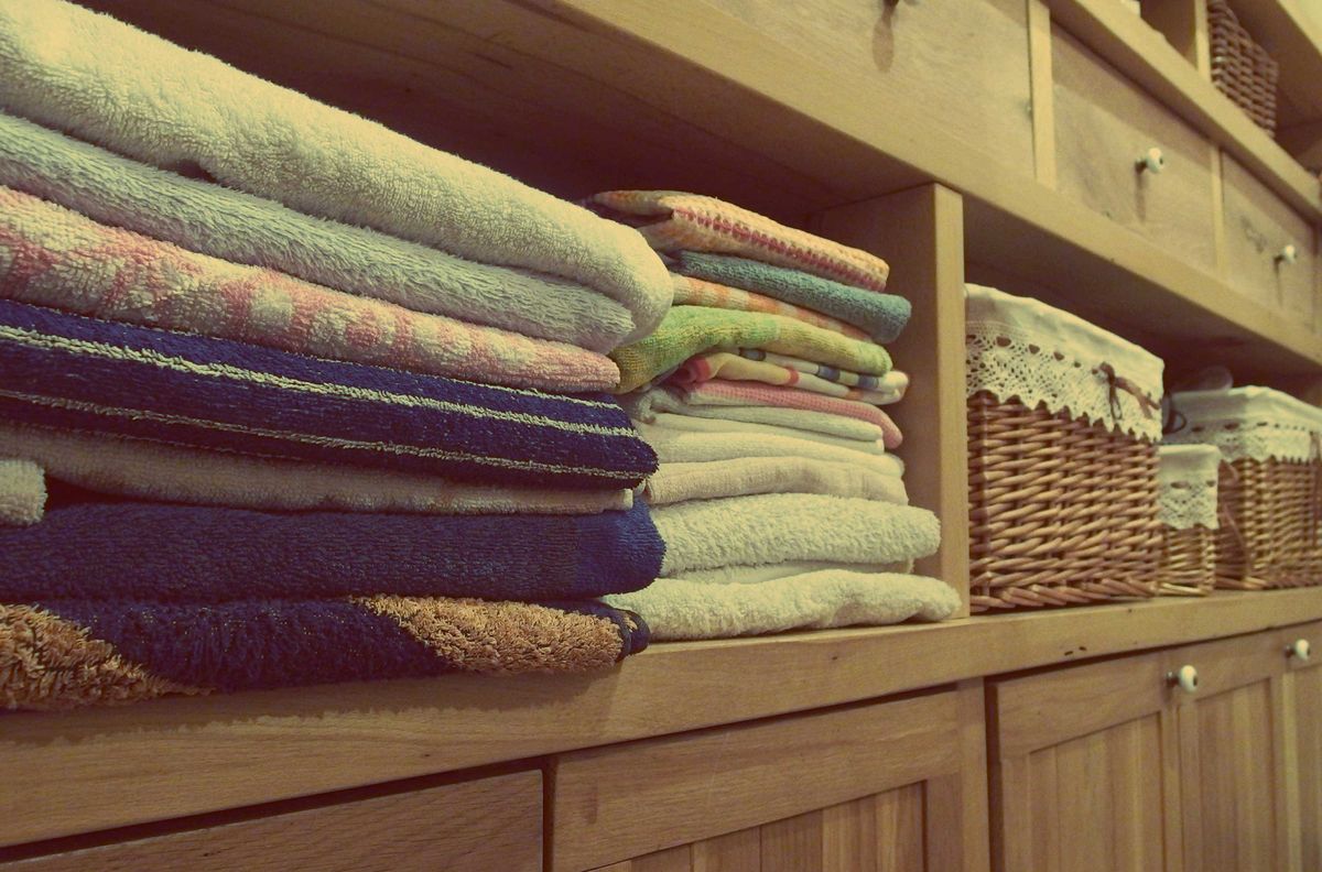 Labeled storage bins and neatly stacked laundry supplies in a tiny laundry closet