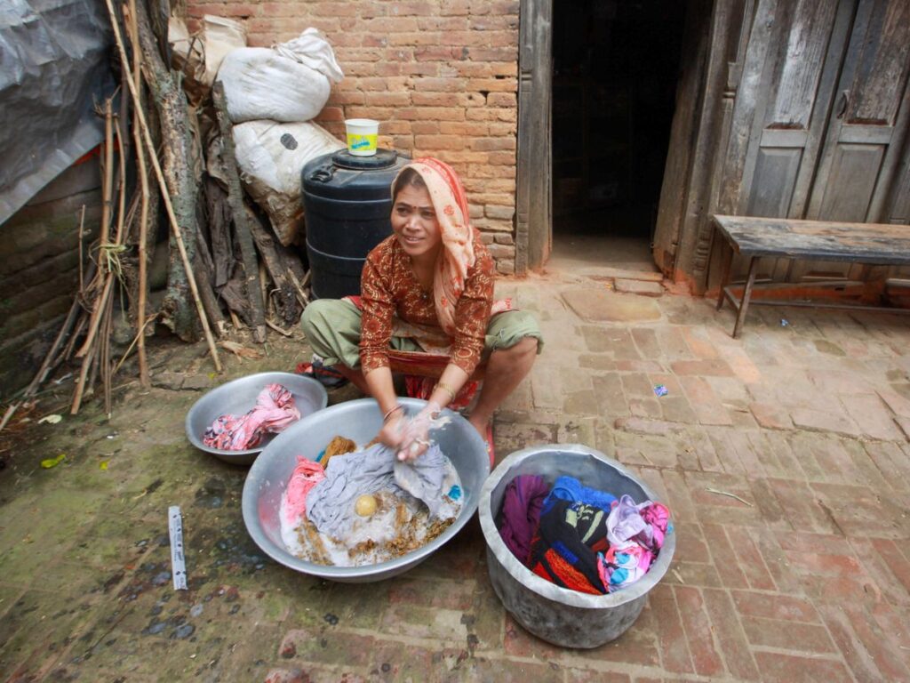 Woman doing laundry without a washing machine by hand washing clothes in bowls