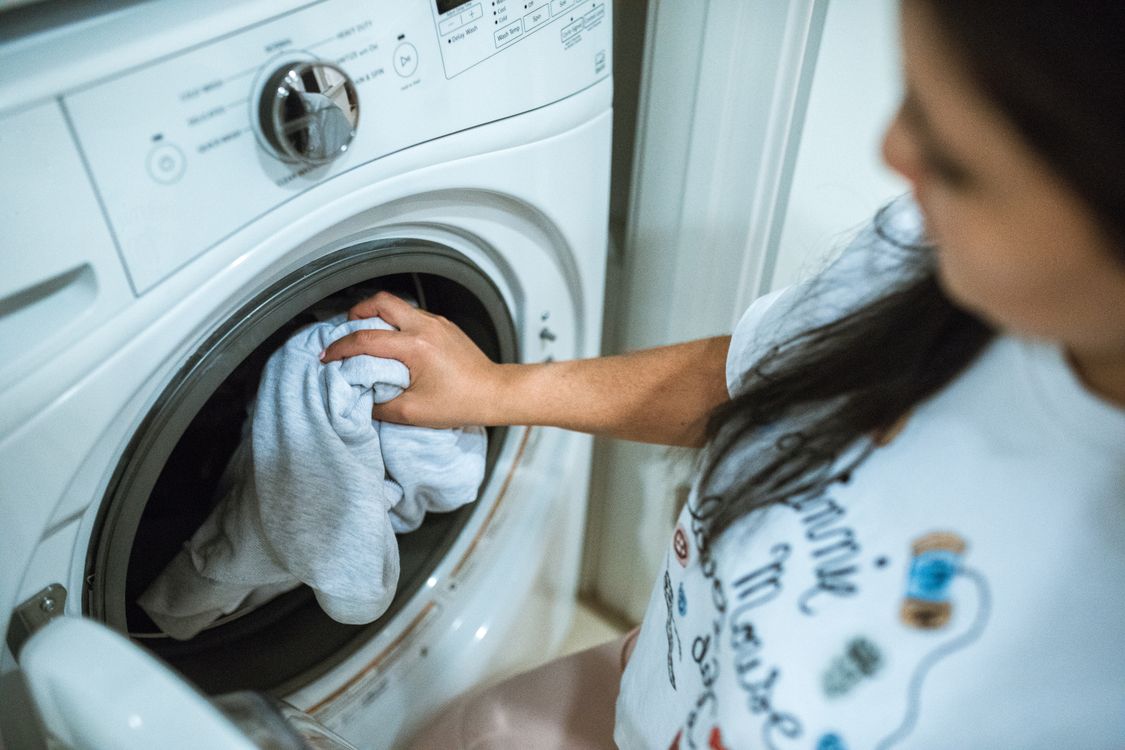 Loading gym clothes into the washer to care for activewear