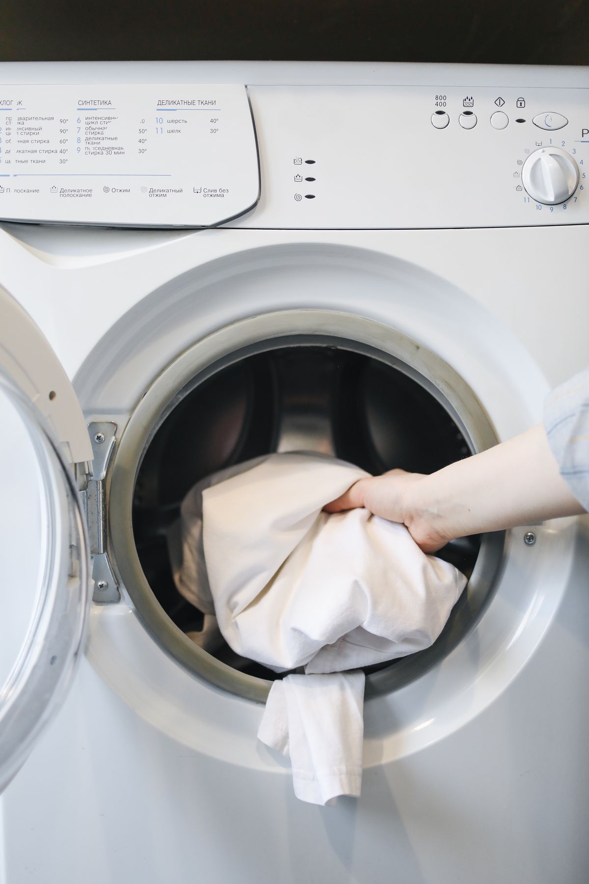 Hand placing a delicate garment into a front-loading washing machine