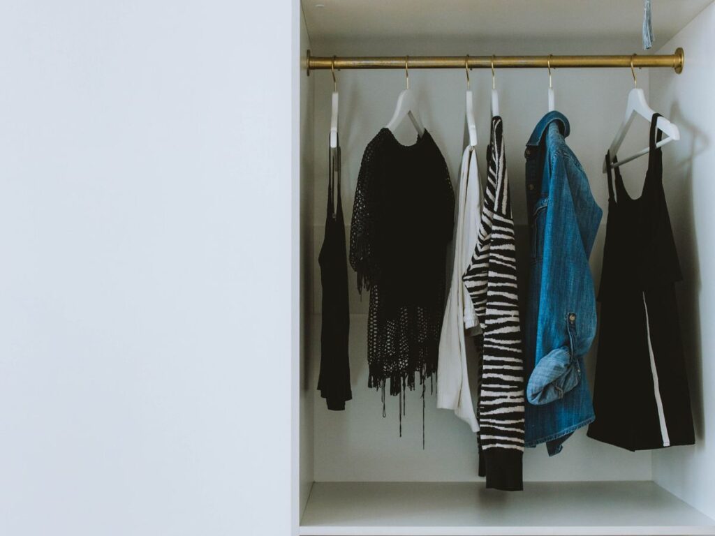 A neatly organized tiny closet with clothes and shoes