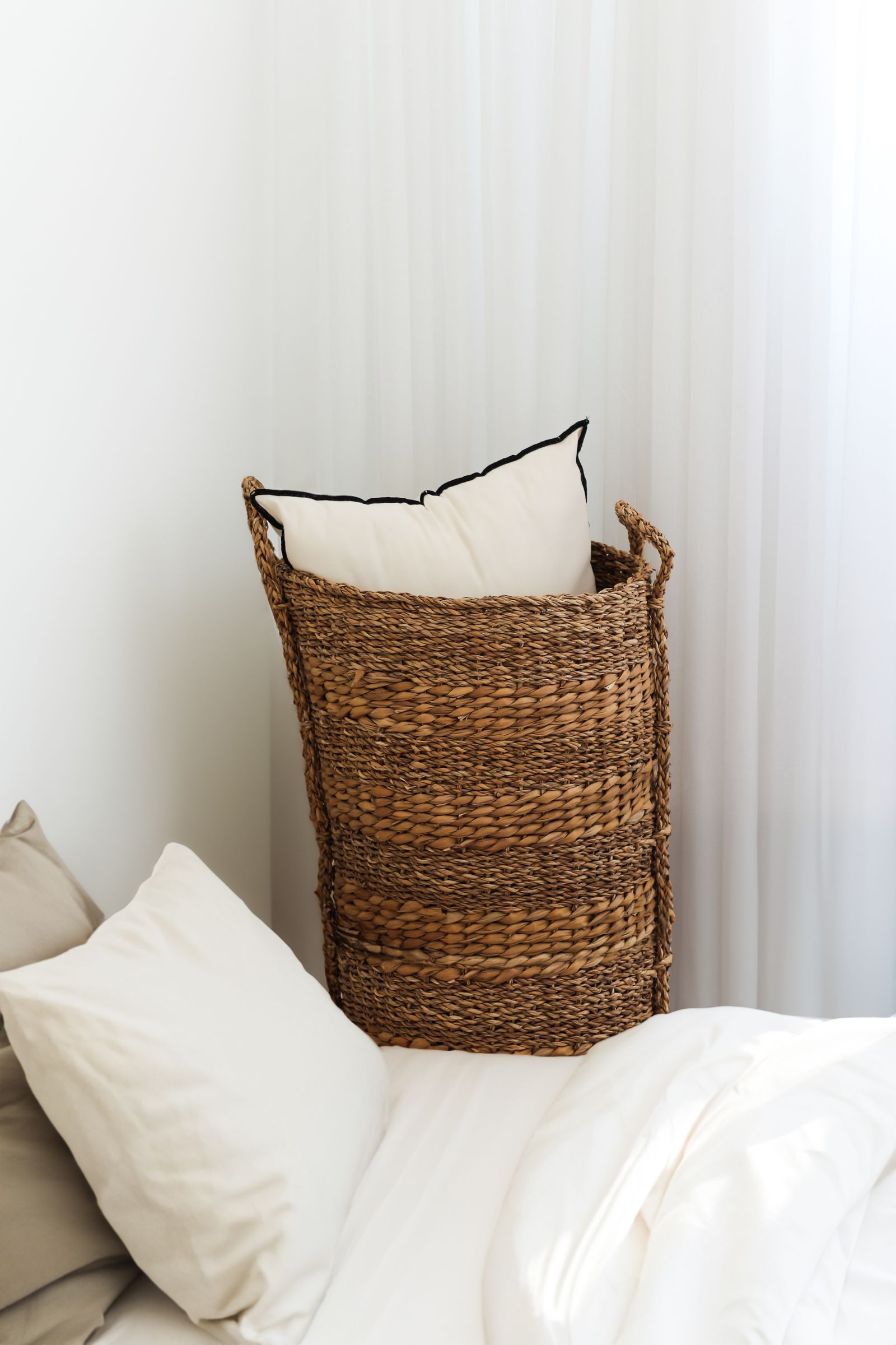 Pillows in a basket with neutral bedding ready for washing