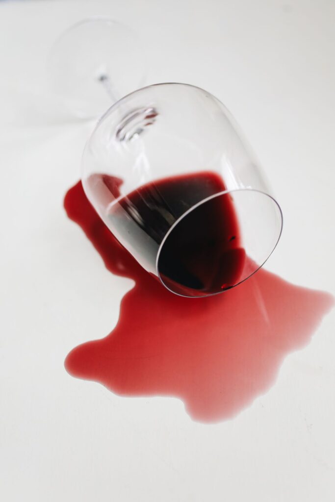 Red wine on clothes: a spilled glass of red wine spreading across a white surface