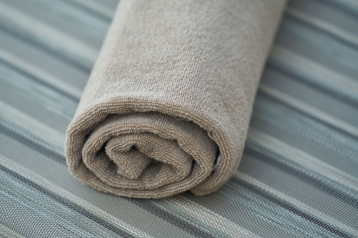 A soft cotton bath towel rolled neatly, best washed every three to four uses