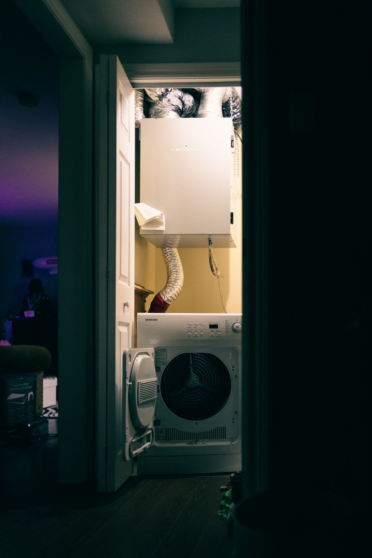 A stacked washer and dryer in a laundry closet with ventilation