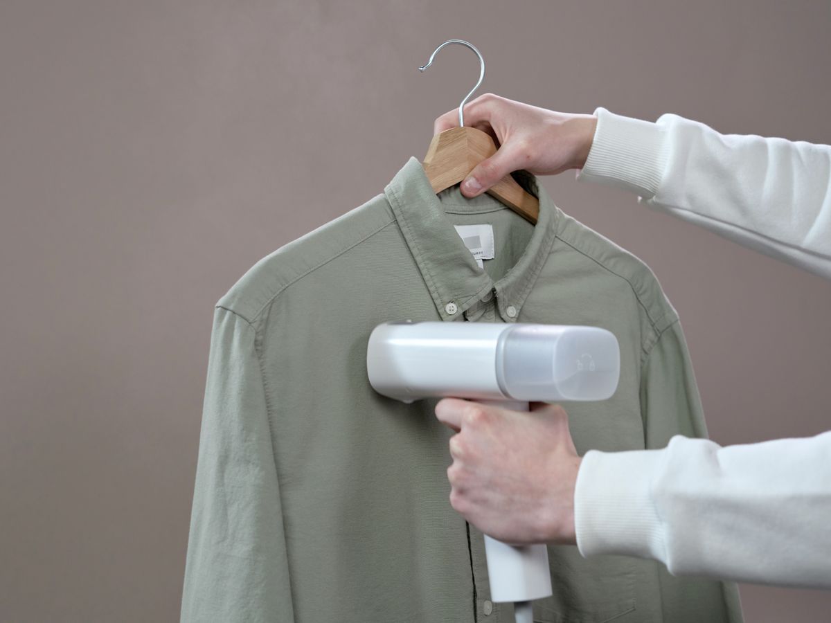 Steaming a shirt with a portable steamer to refresh and smooth the fabric