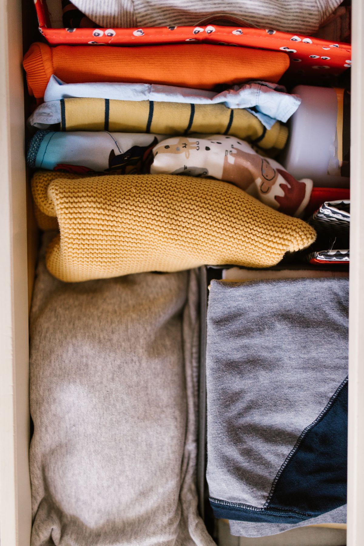 Sweaters folded into neat rectangles and stacked in a drawer to keep their shape