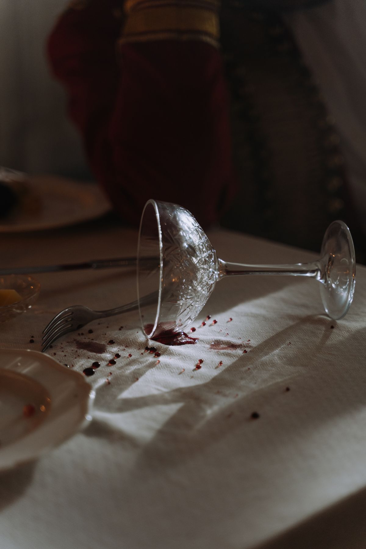 A tipped wine glass leaving a fresh red wine stain on a tablecloth to blot immediately