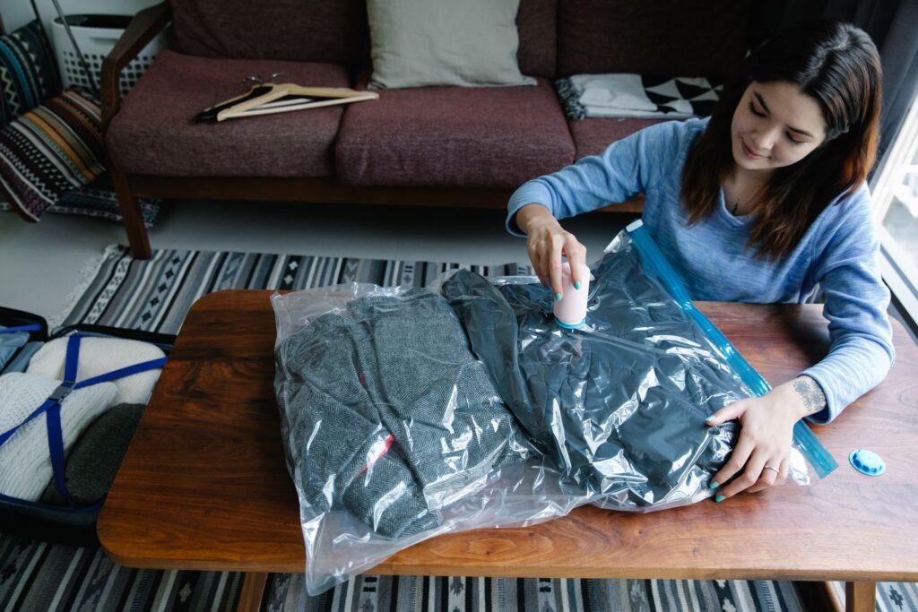 Person using vacuum storage bags to compress folded clothes at home
