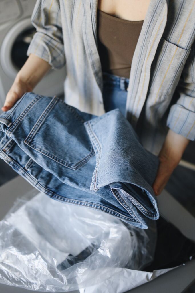 How often to wash jeans towels and bedding: a person holding folded jeans in a laundry room
