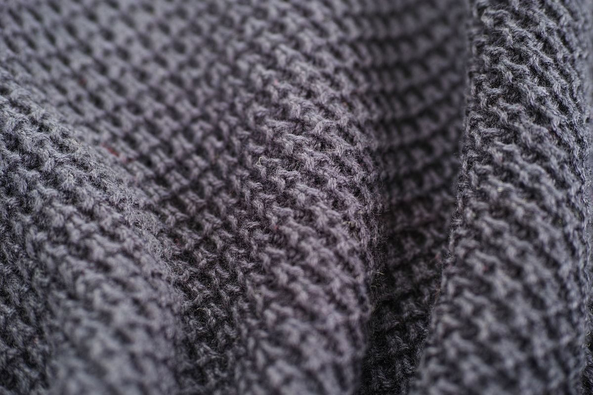 Close-up of gray wool knit texture where sweater fibers pill